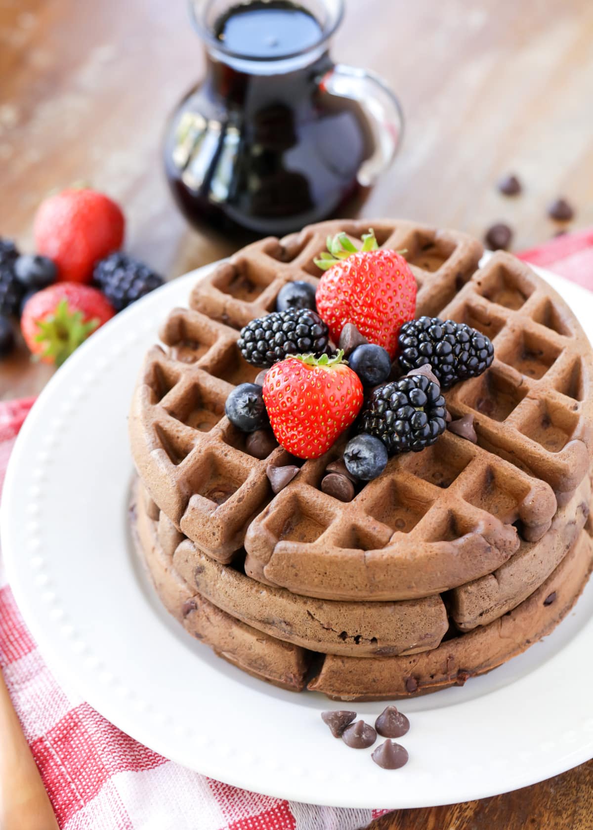 Stack of chocolate waffles topped with fresh berries.