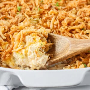Close up of scooping french onion chicken casserole from a baking dish.