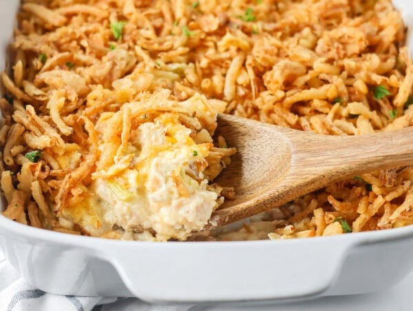 Close up of scooping french onion chicken casserole from a baking dish.