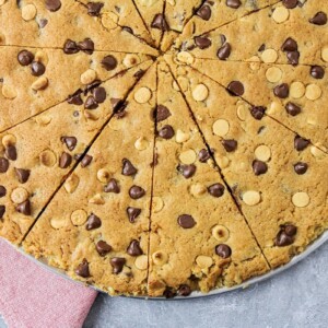 A sliced giant chocolate chip cookie on a pizza plate.
