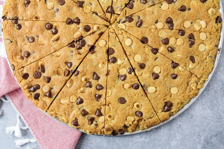 A sliced giant chocolate chip cookie on a pizza plate.