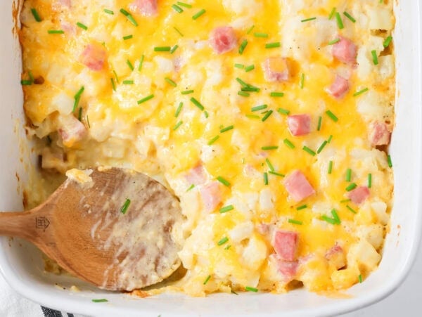 Ham and potato casserole in baking dish with scoop dished out.