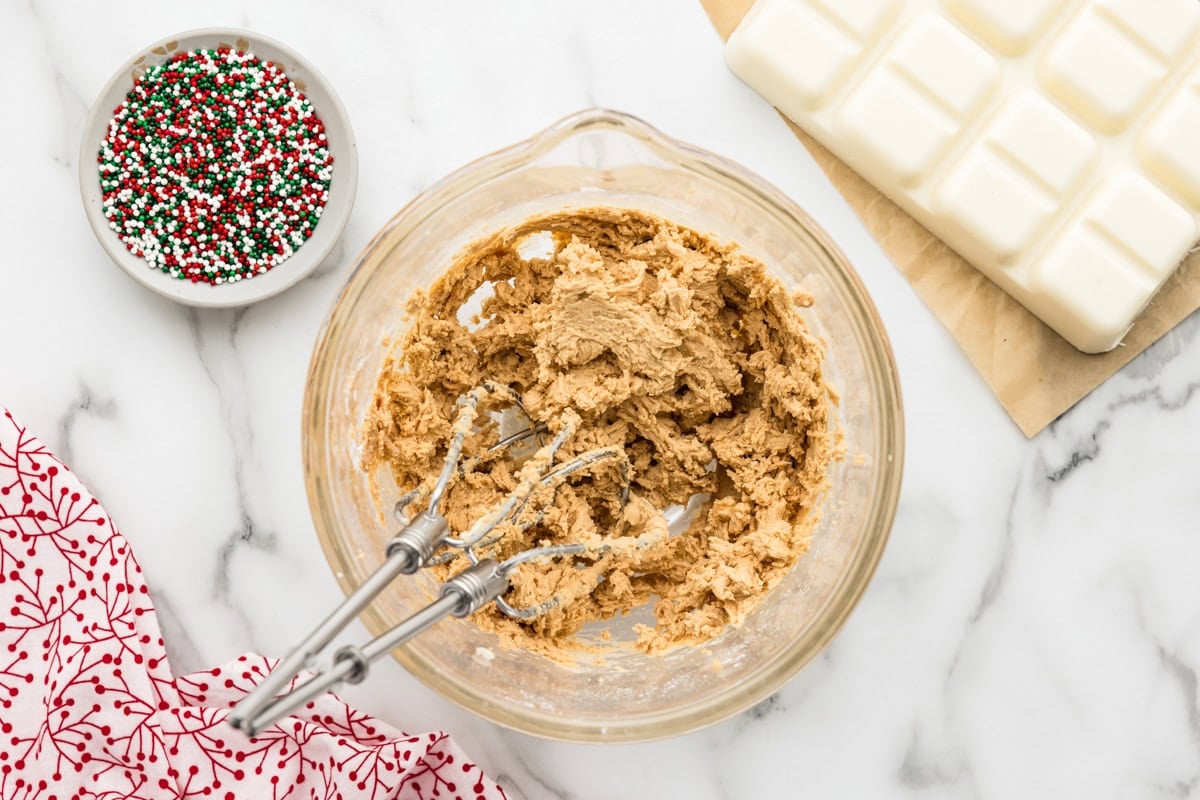 Mixing peanut butter snowballs batter in a glass bowl.