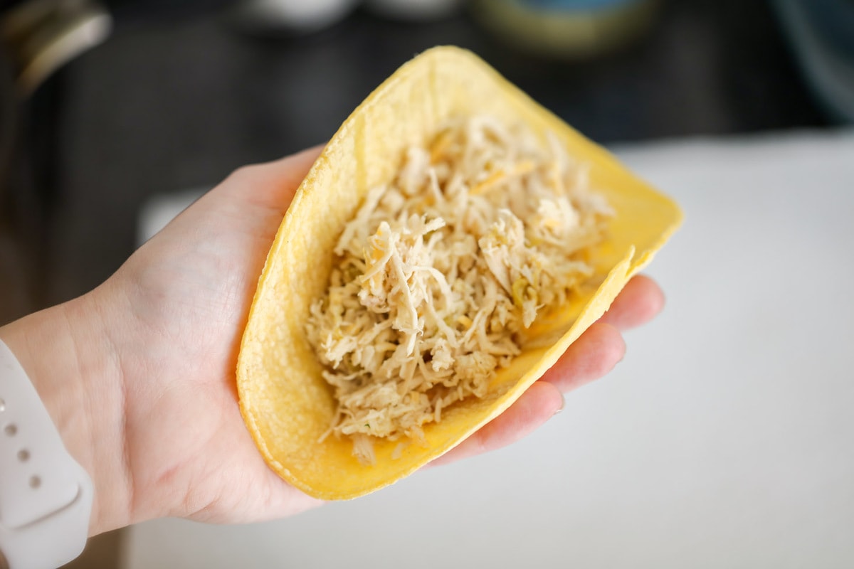 Filling corn tortillas with shredded chicken.