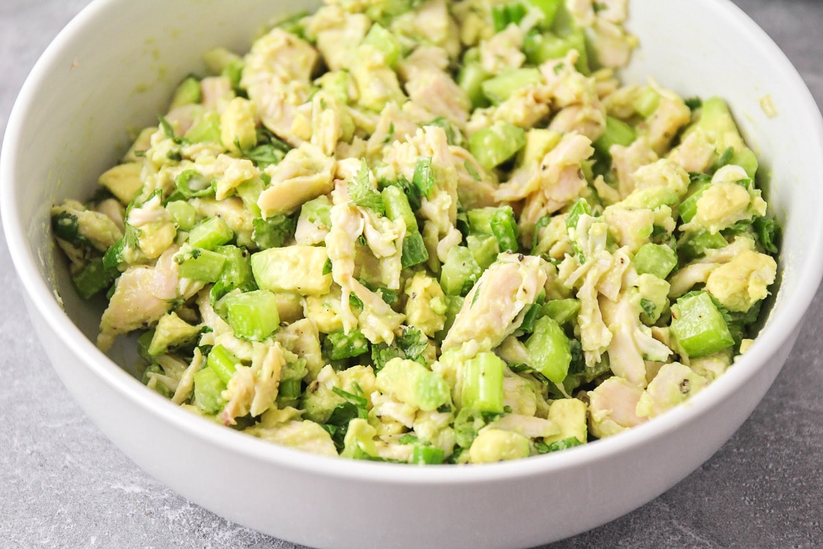 White bowl filled with avocado chicken salad filling.