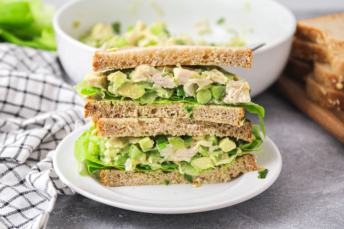 Avocado chicken salad served on sandwiches on a white plate.