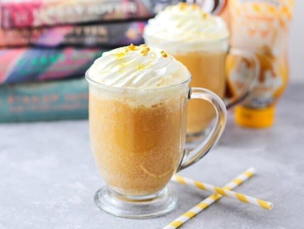 Glass mug of homemade Harry Potter Butterbeer recipe with books in the background.