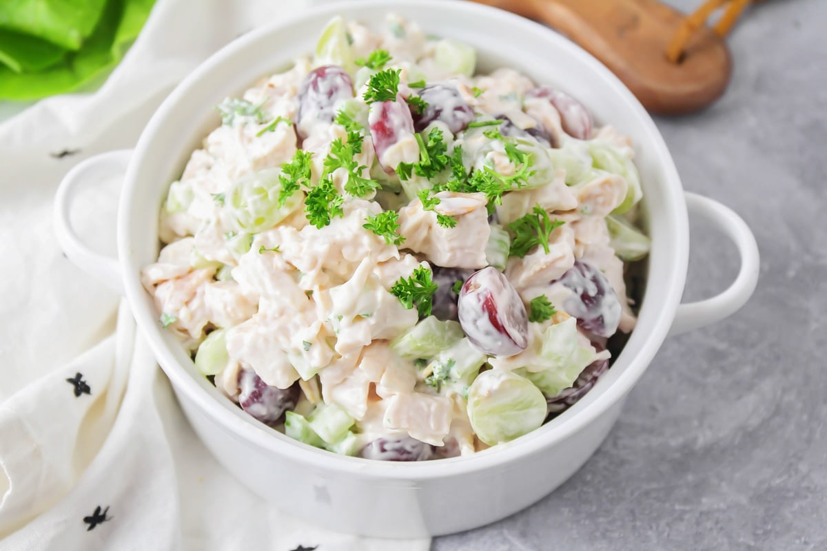 Chicken salad with grapes served up in a white bowl.