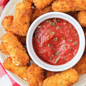 A plate of mozzarella sticks served with marinara sauce.