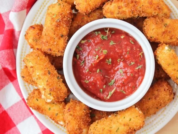 A plate of mozzarella sticks served with marinara sauce.