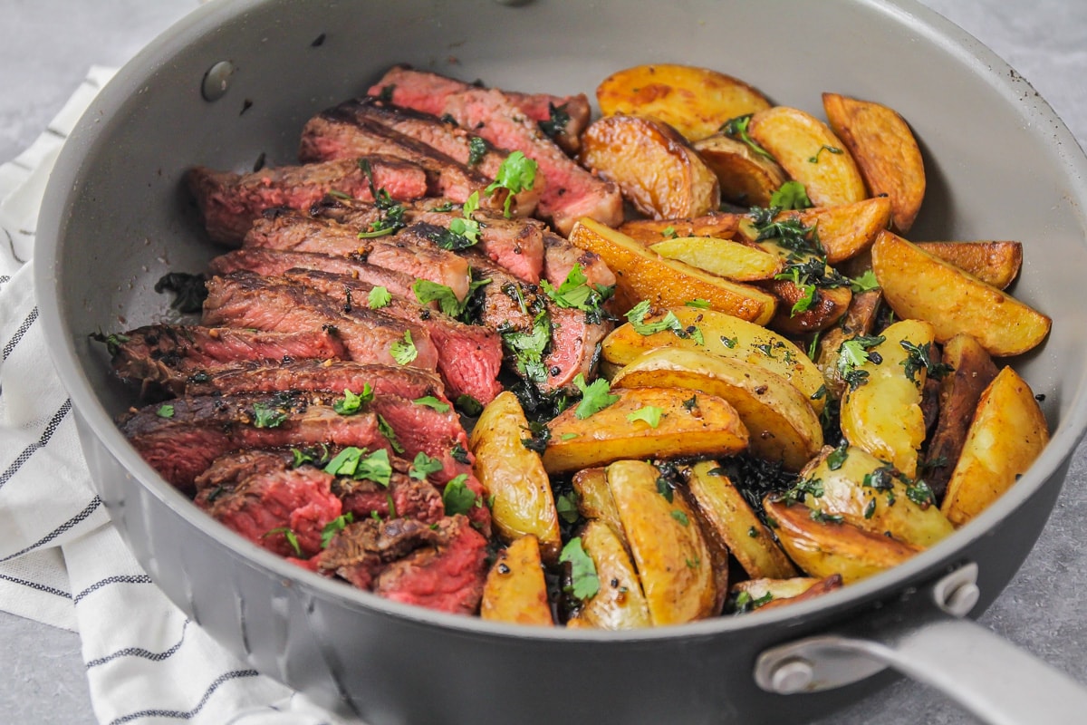 Winter Dinner Ideas - steak and potatoes in a skillet topped with chopped parsley. 