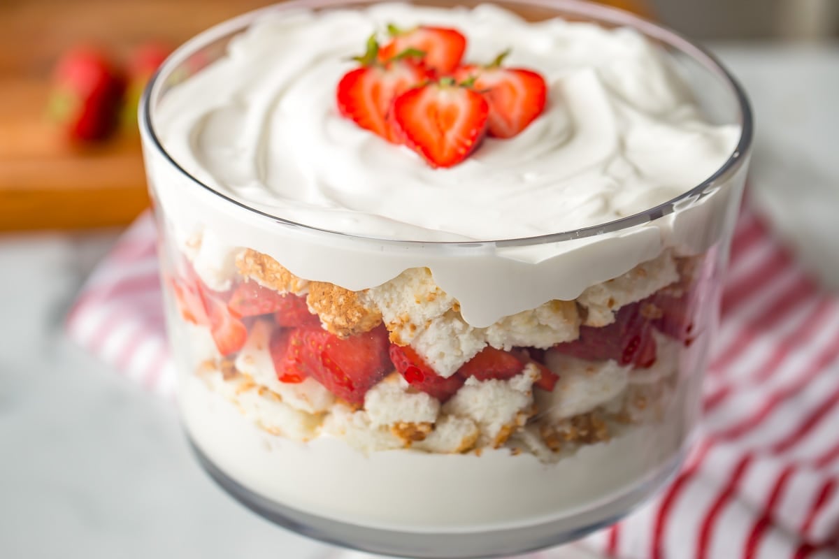 Strawberries and Cream angel food cake trifle topped with whipped cream and fresh strawberries.