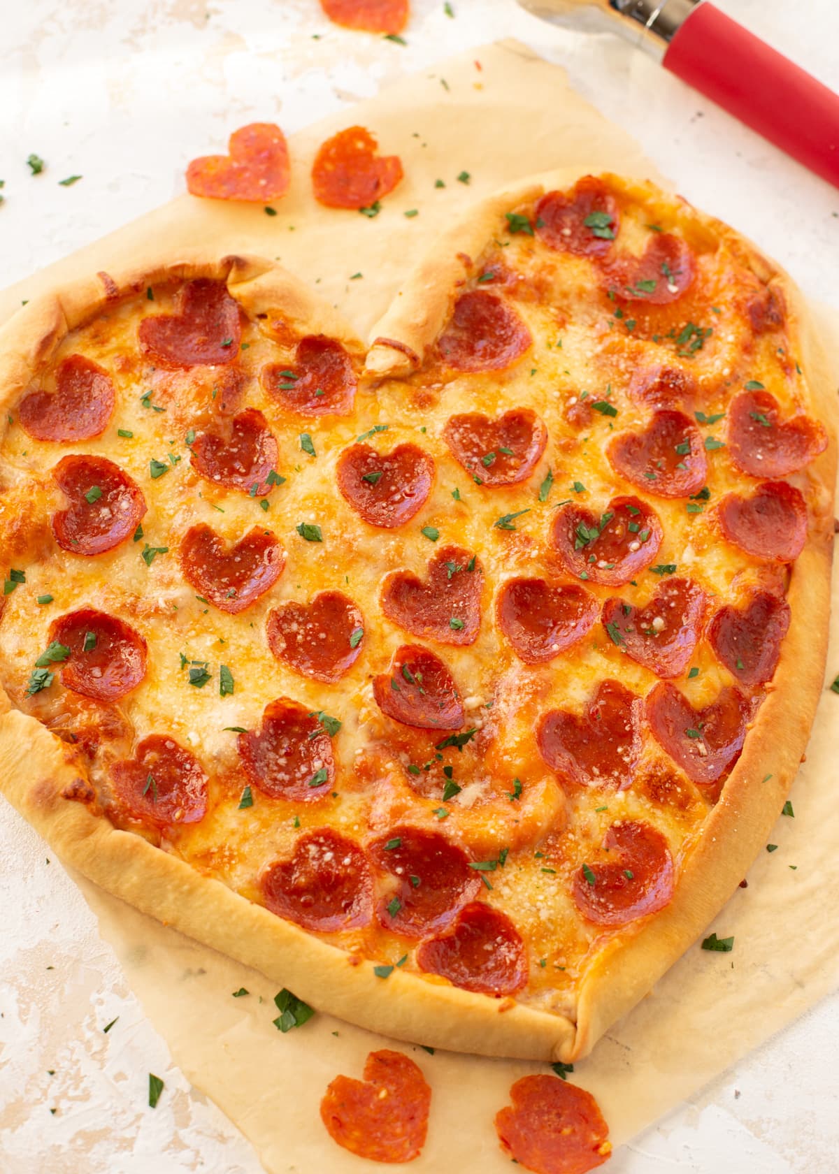 Baked heart shaped Pizza covered in heart pepperonis.
