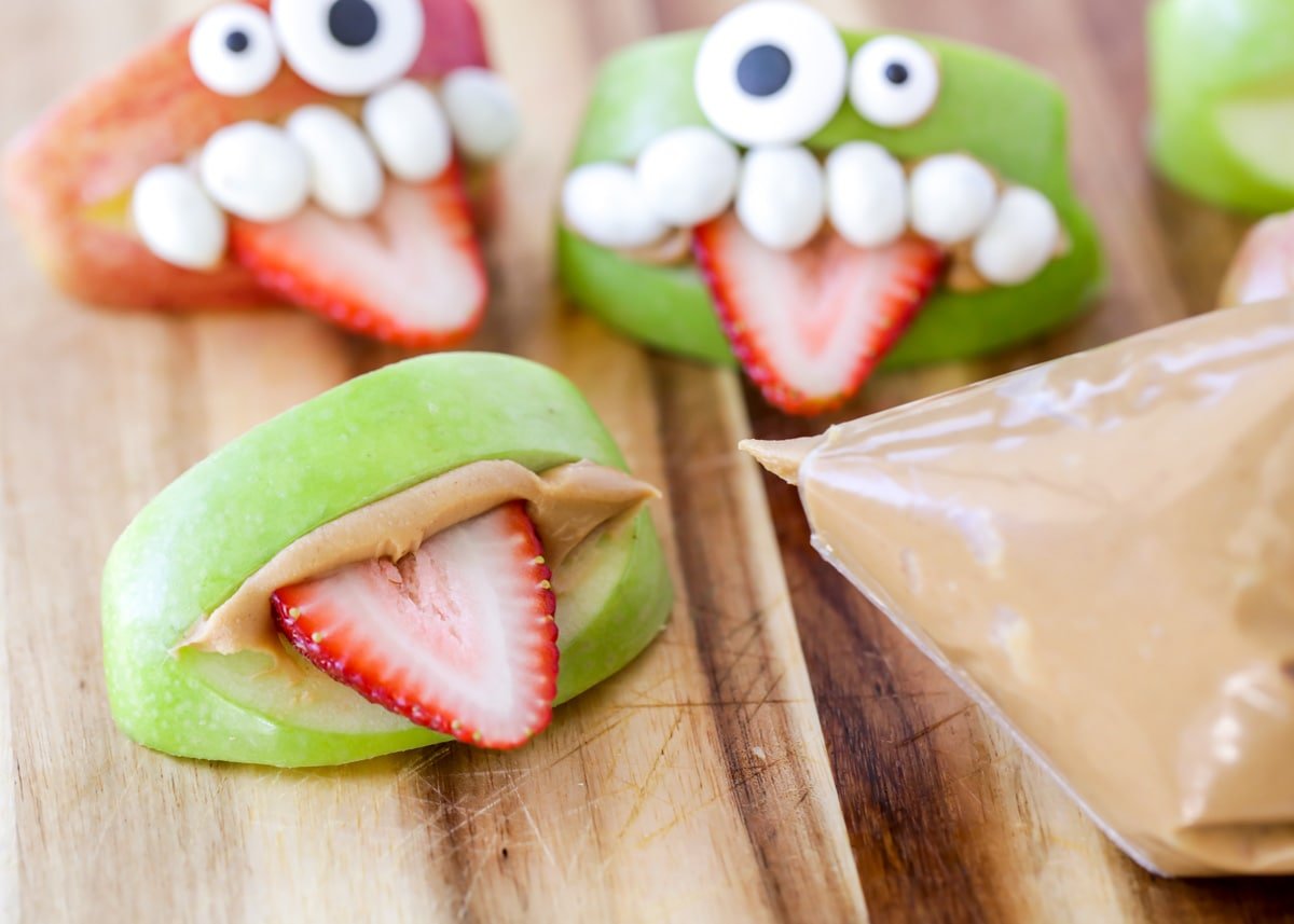 Assembling apple monster teeth with peanut butter and strawberries.