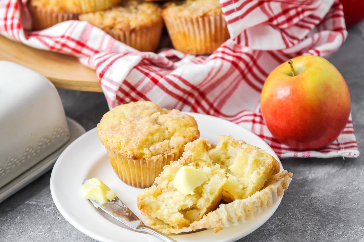 Apple muffins served on a white plate and topped with butter