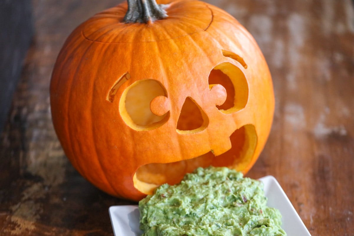 Halloween snacks - a jack-o-lantern barfing pumpkin guacamole.