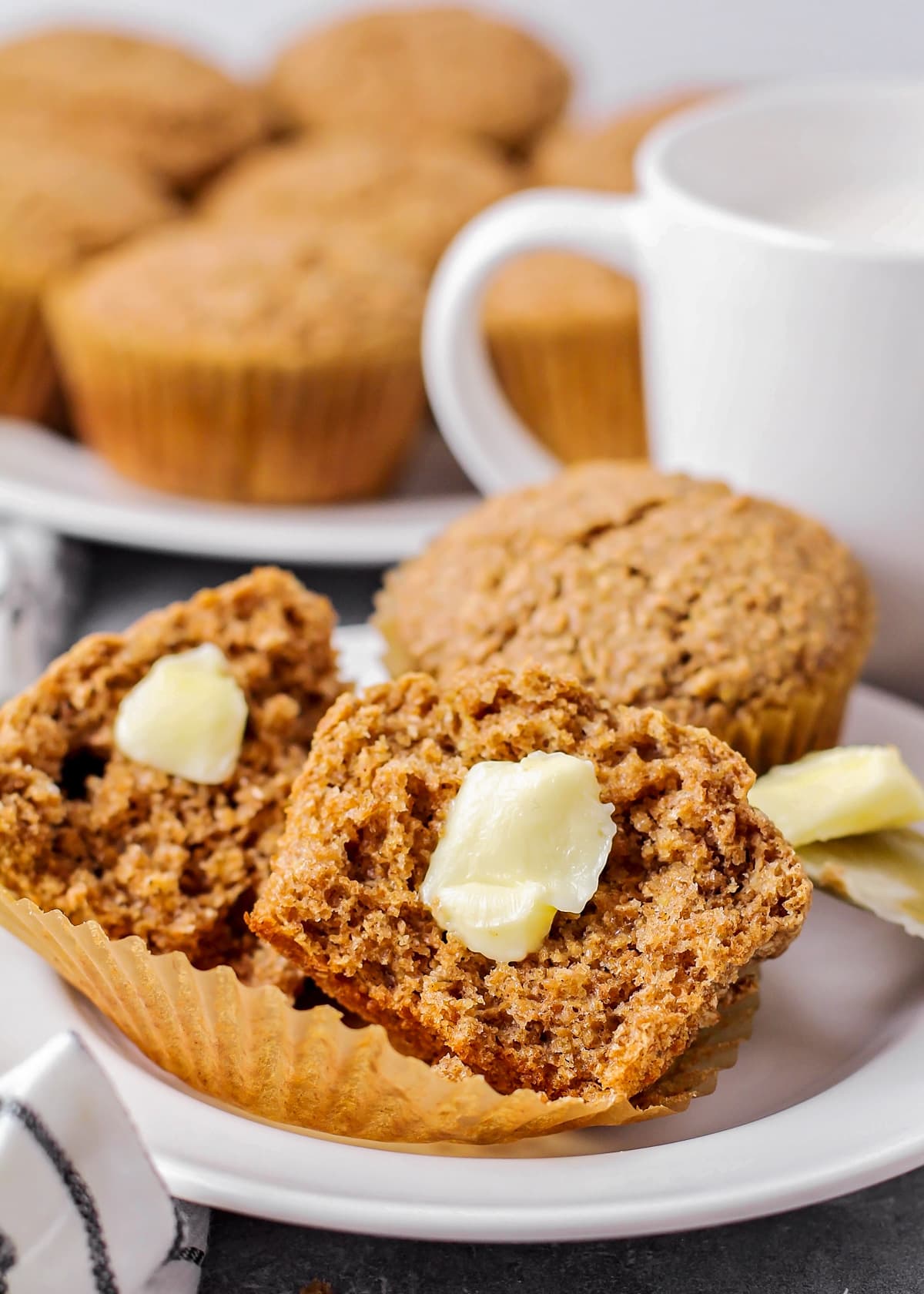 A bran muffin split in halg and topped with butter.