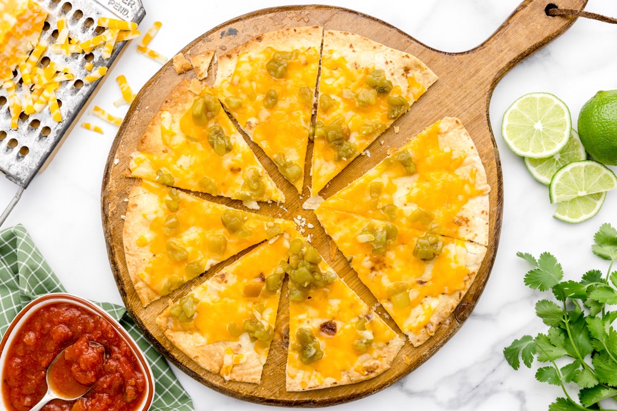 A sliced baked cheese crisp topped with green chili.