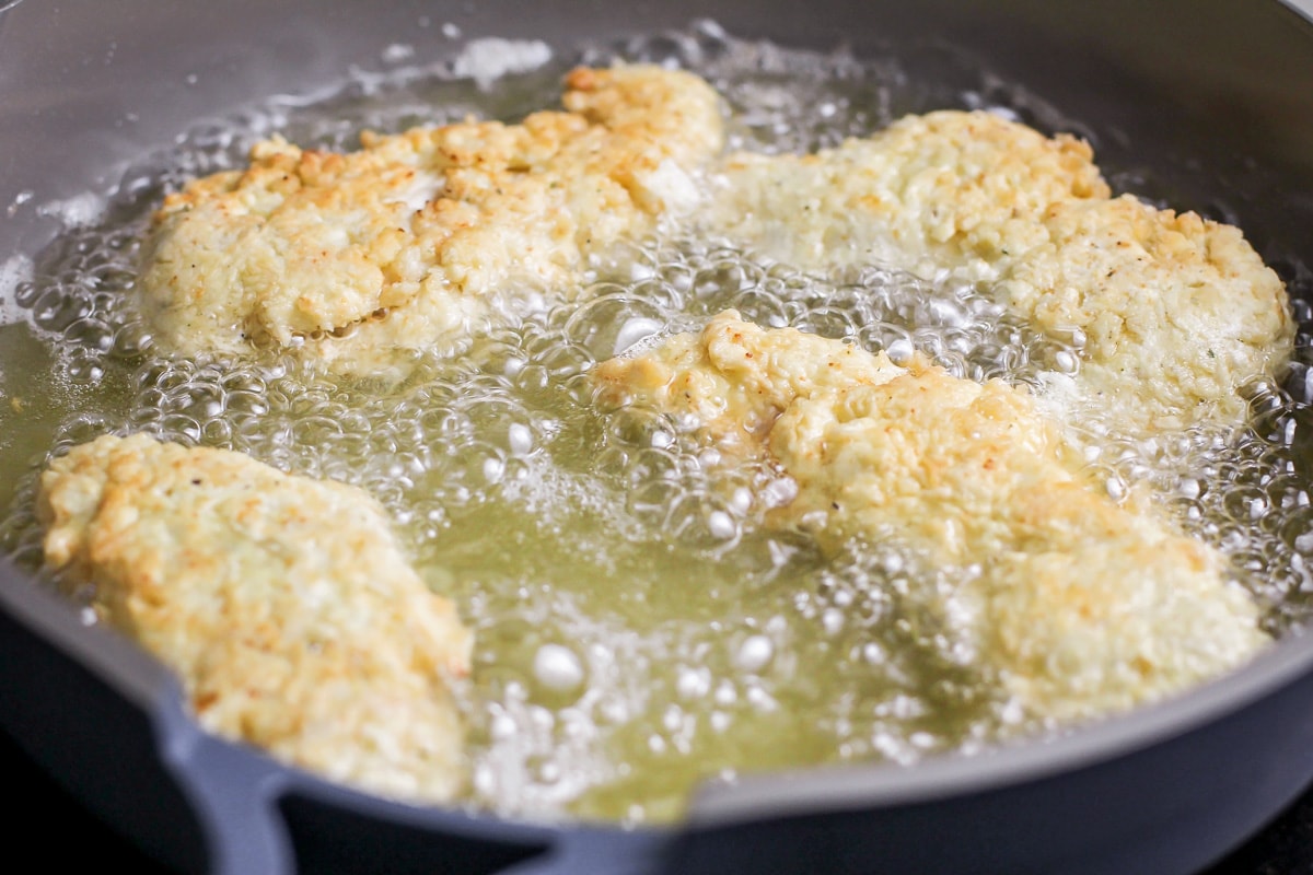 Frying chicken fingers in a skillet of oil.