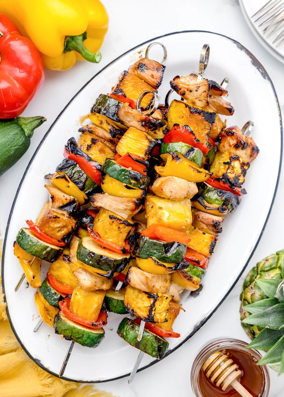 Grilled chicken kabobs on metal skewers, served on a white platter.