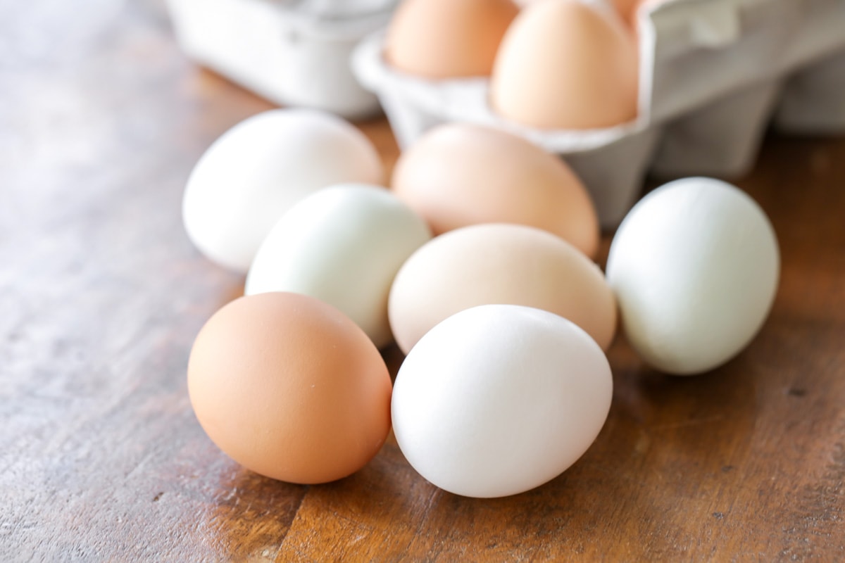 Several brown and white eggs sitting on a wood surface. 