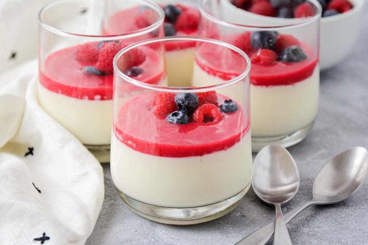 Raspberry sauce a top a vanilla panna cotta topped with fresh berries.