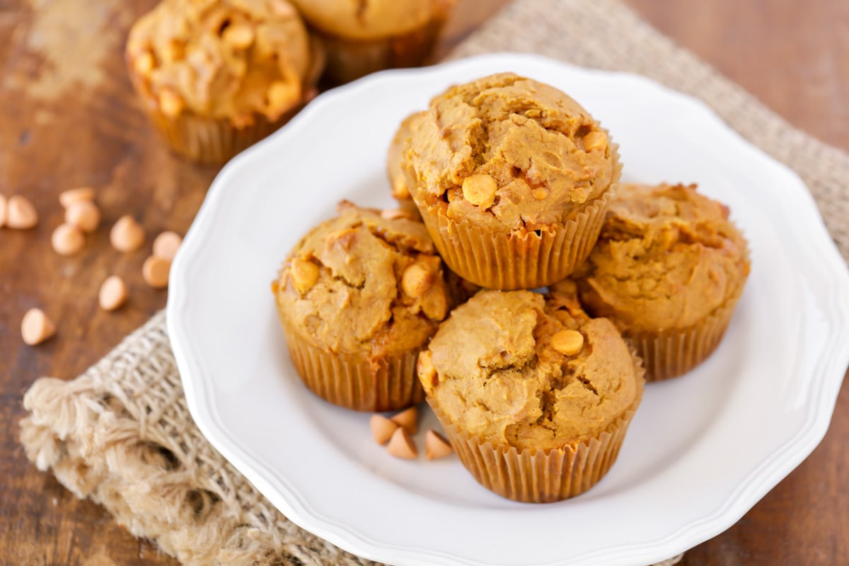 Five pumpkin butterscotch muffins stacked on a white plate.