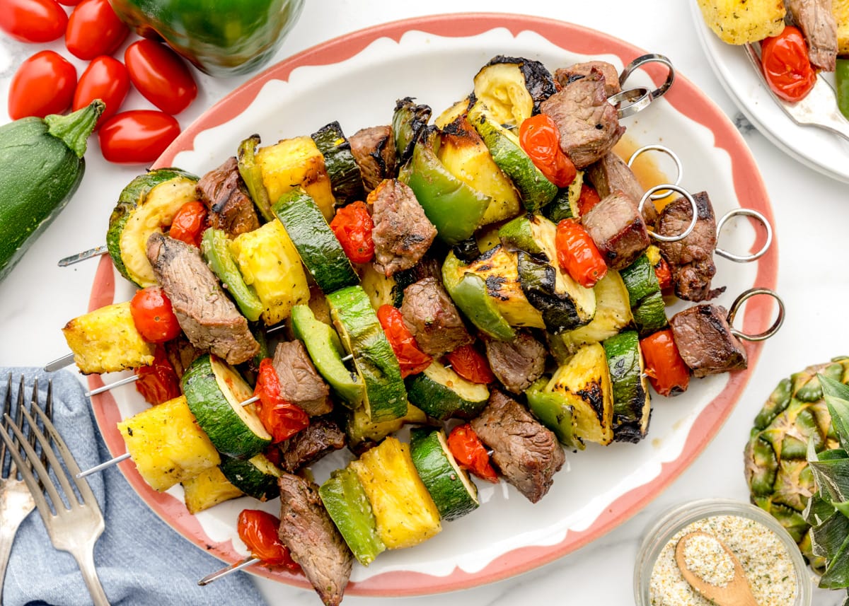 Steak kabobs grilled and served on a white platter.