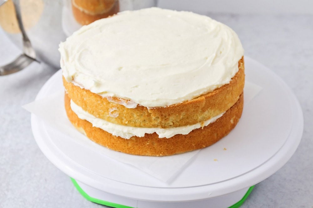 Putting together vanilla cake layers on cake stand.