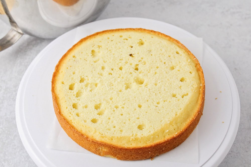 Vanilla cake that has been leveled and added to cake stand.
