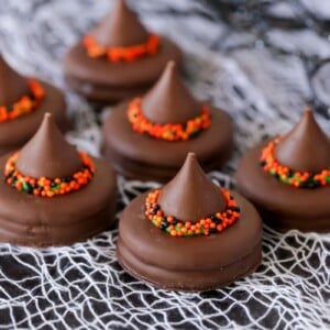 Several witch hat cookies on a decorative cloth.