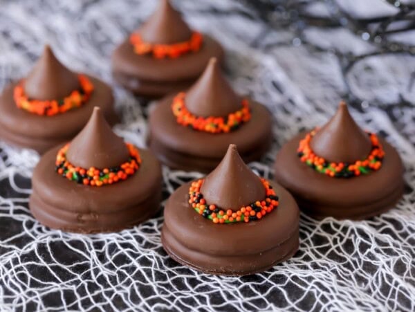 Several witch hat cookies on a decorative cloth.