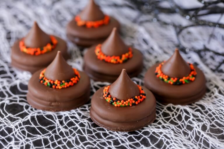 Several witch hat cookies on a decorative cloth.