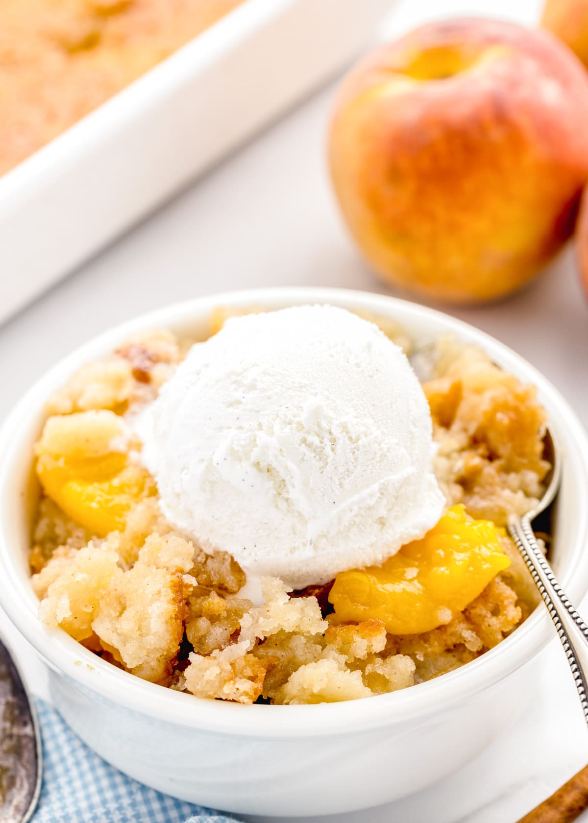 Bowl of bisquick peach cobbler topped with a scoop of vanilla ice cream