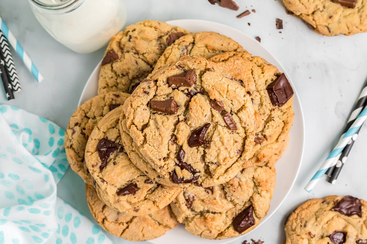 Plate filled with stacked golden brown chocolate chunk cookies.