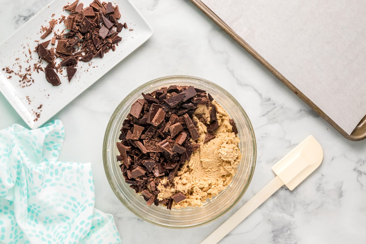 Mixing chocolate into chocolate chunk cookies dough.