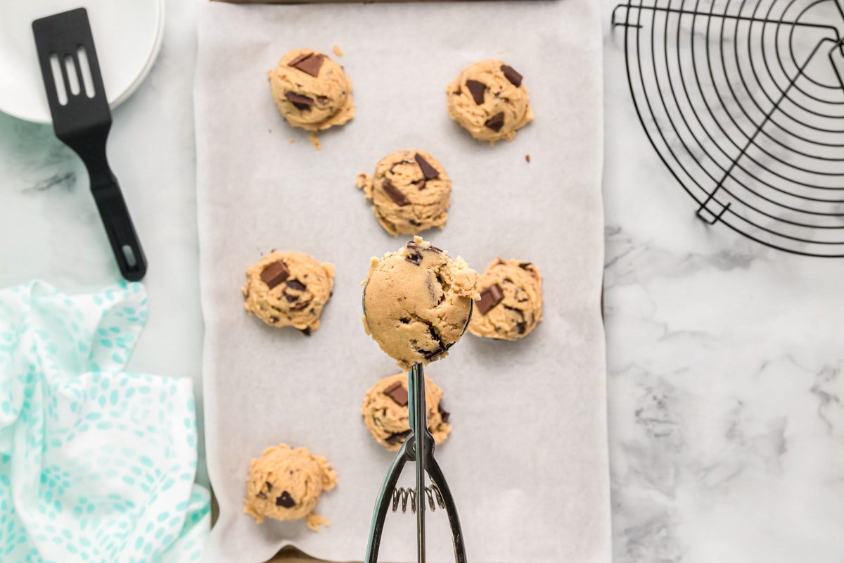 Scooping chocolate chunk cookies batter for baking.