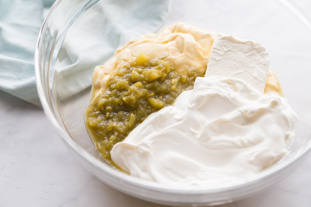 Creamy chicken enchilada ingredients in glass bowl.