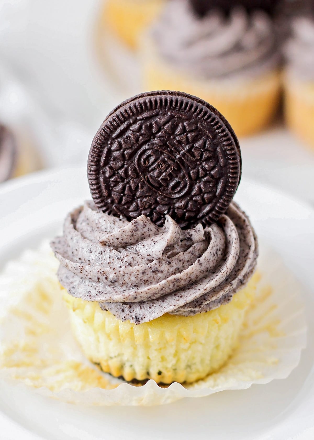 Oreo topped cookies and cream cupcake on a white platter.