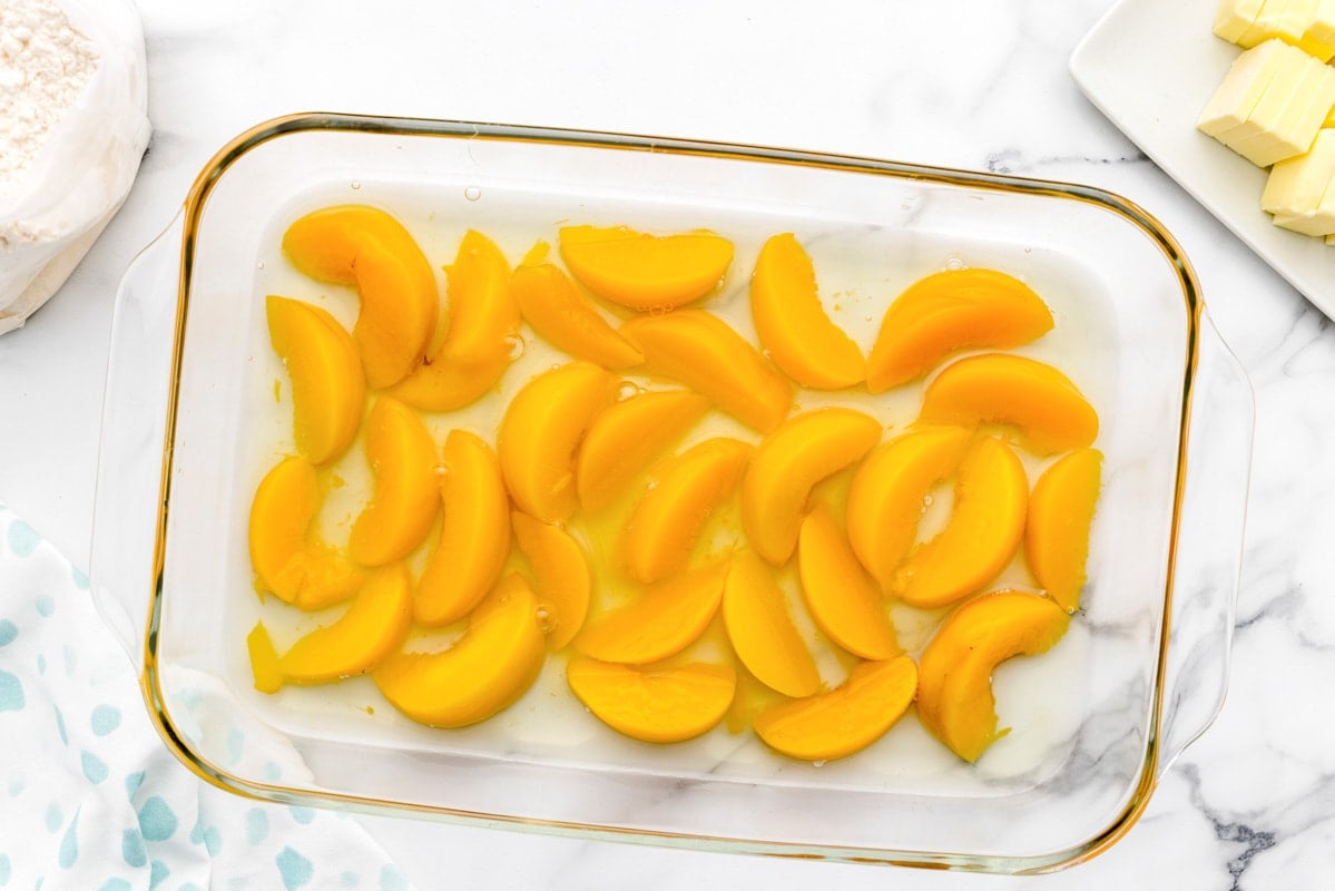 EASY Peach Cobbler with Cake Mix layered in a glass dish.