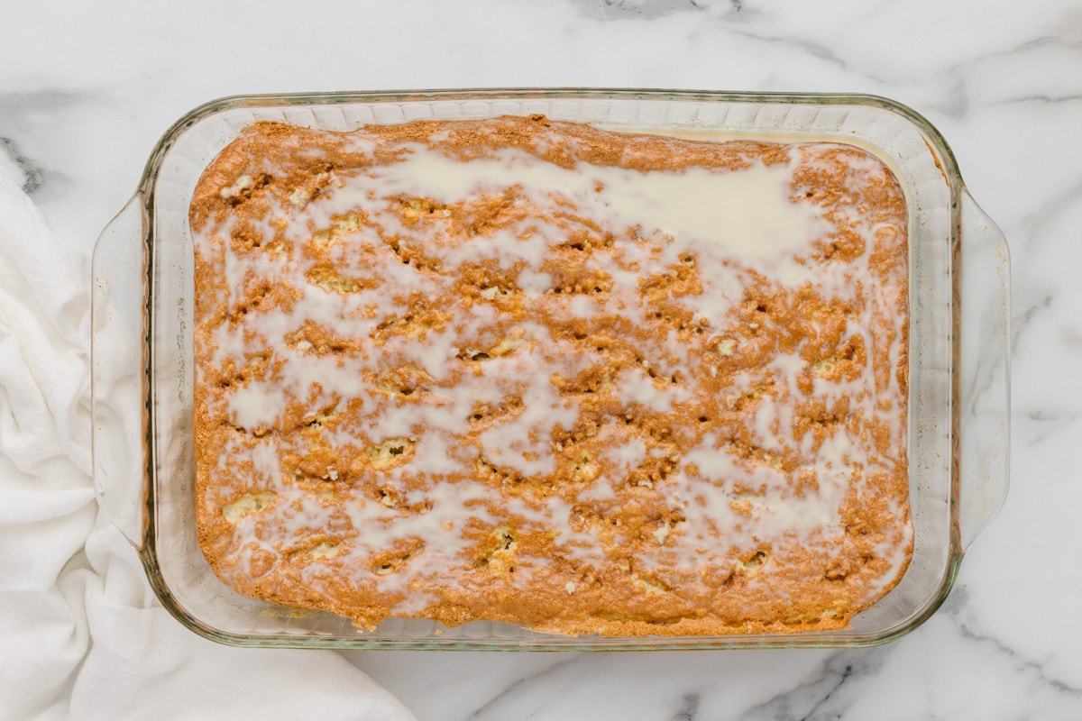Pouring the three milk mixture over the cake.