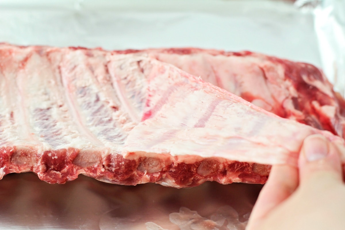Prepping ribs for baking by removing fat.