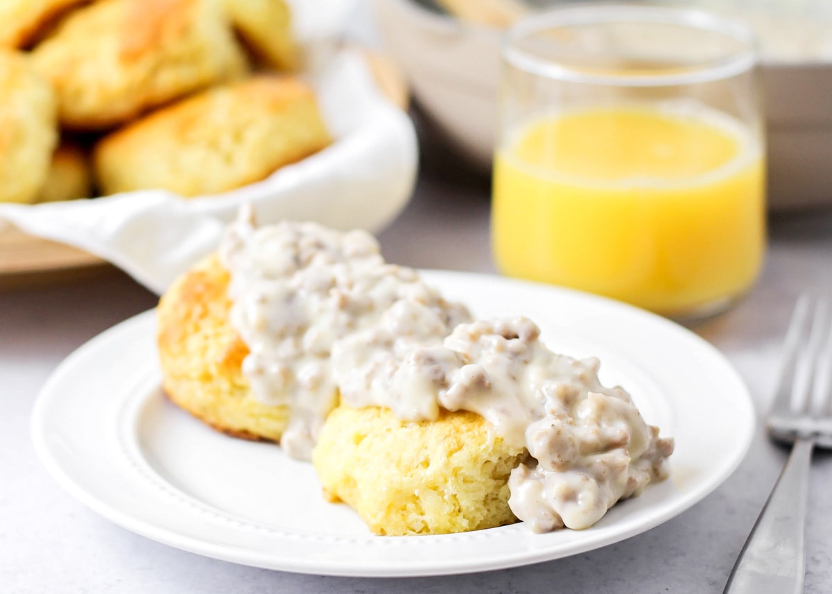 Biscuits and gravy served with a glass of fresh orange juice.