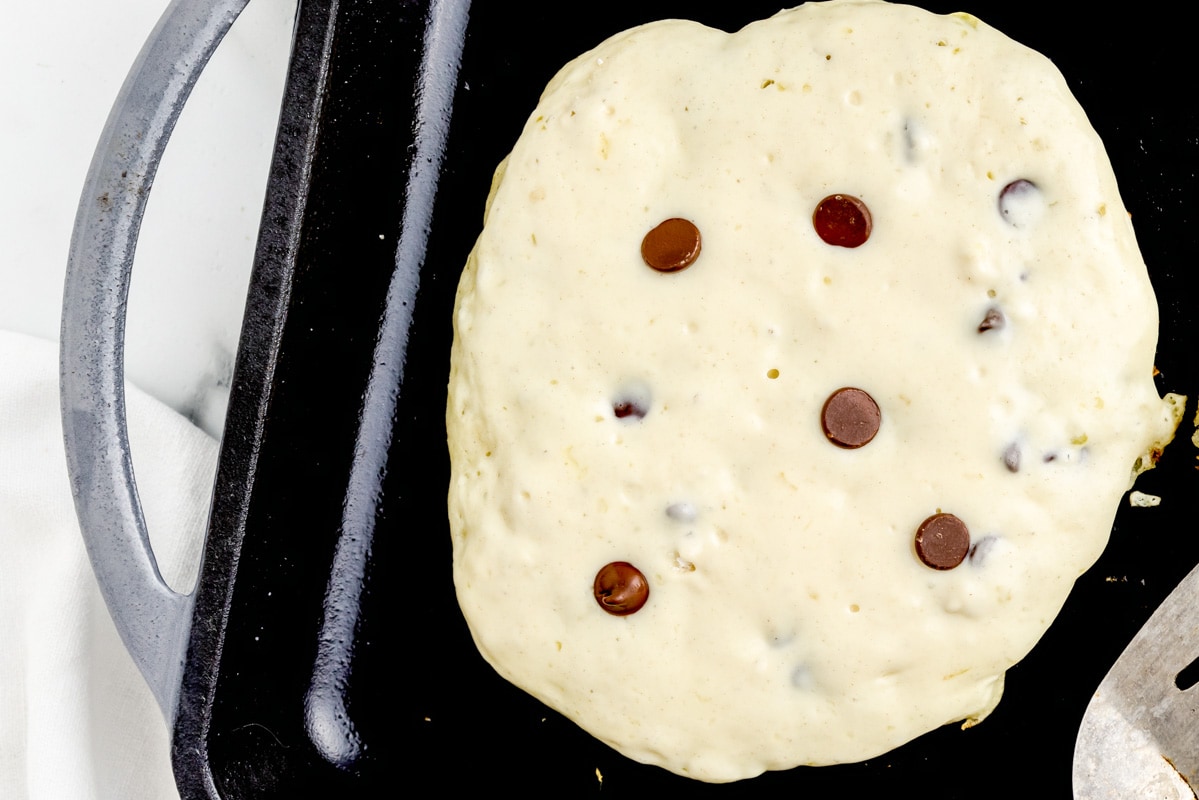 Cooking chocolate chip pancakes on a griddle.