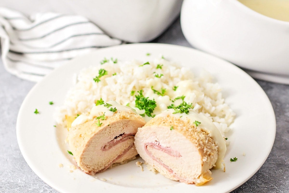 Chicken cordon bleu cut in half on a plate with a side of mashed potatoes.