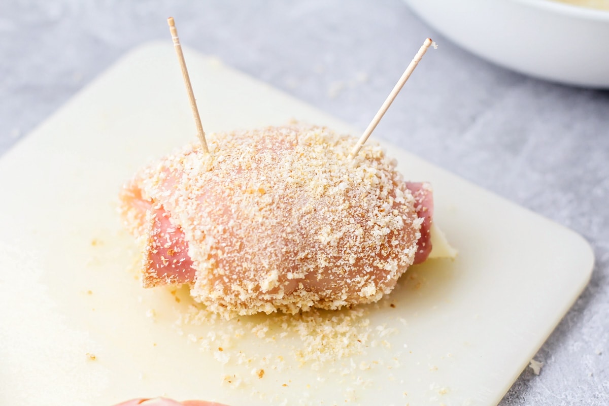 A raw piece of chicken cordon bleu rolled up and held together with toothpicks.