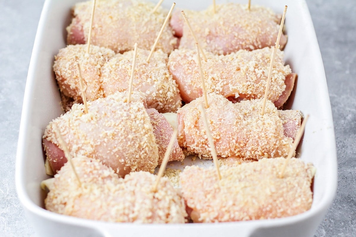 Eight pieces of chicken cordon bleu in a baking dish ready to go in the oven.