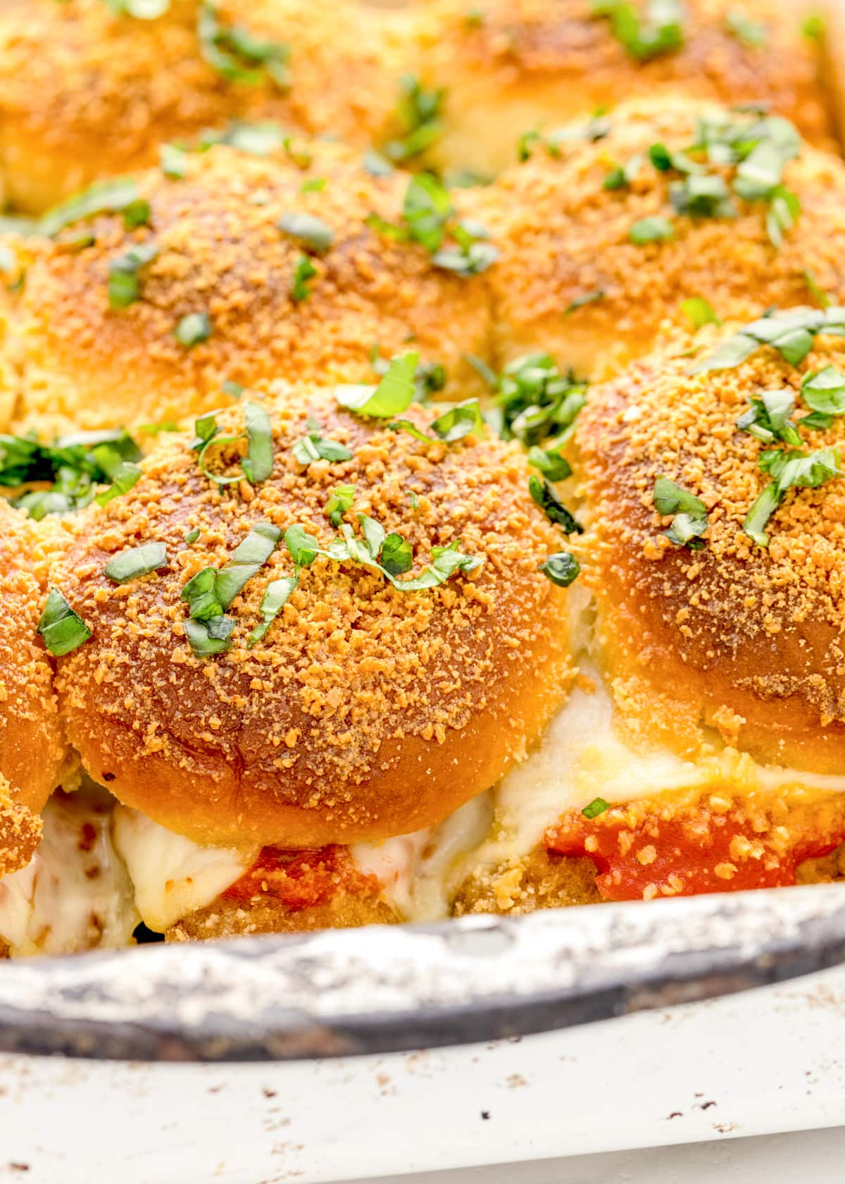 Close up of chicken parmesan sliders topped with herbs.