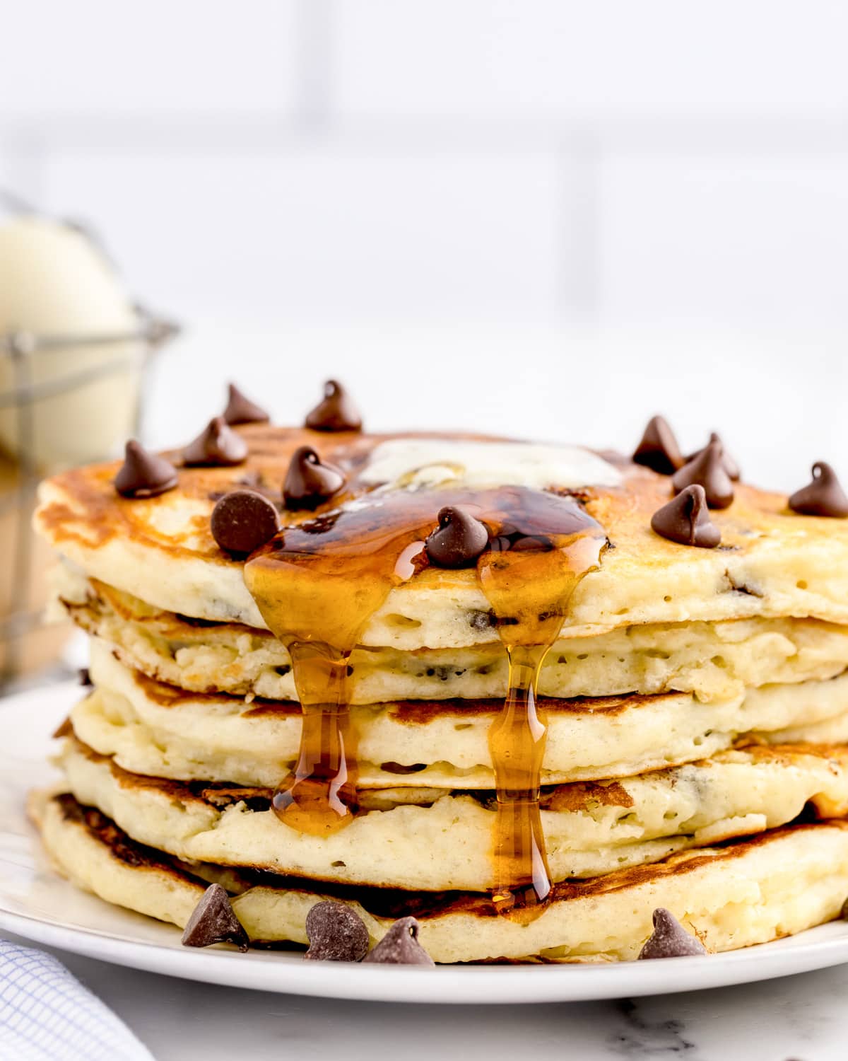 Syrup and butter running down the sides of a stack of chocolate chip pancakes.