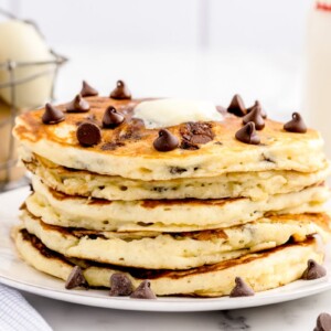 A stack of chocolate chip pancakes topped wither butter